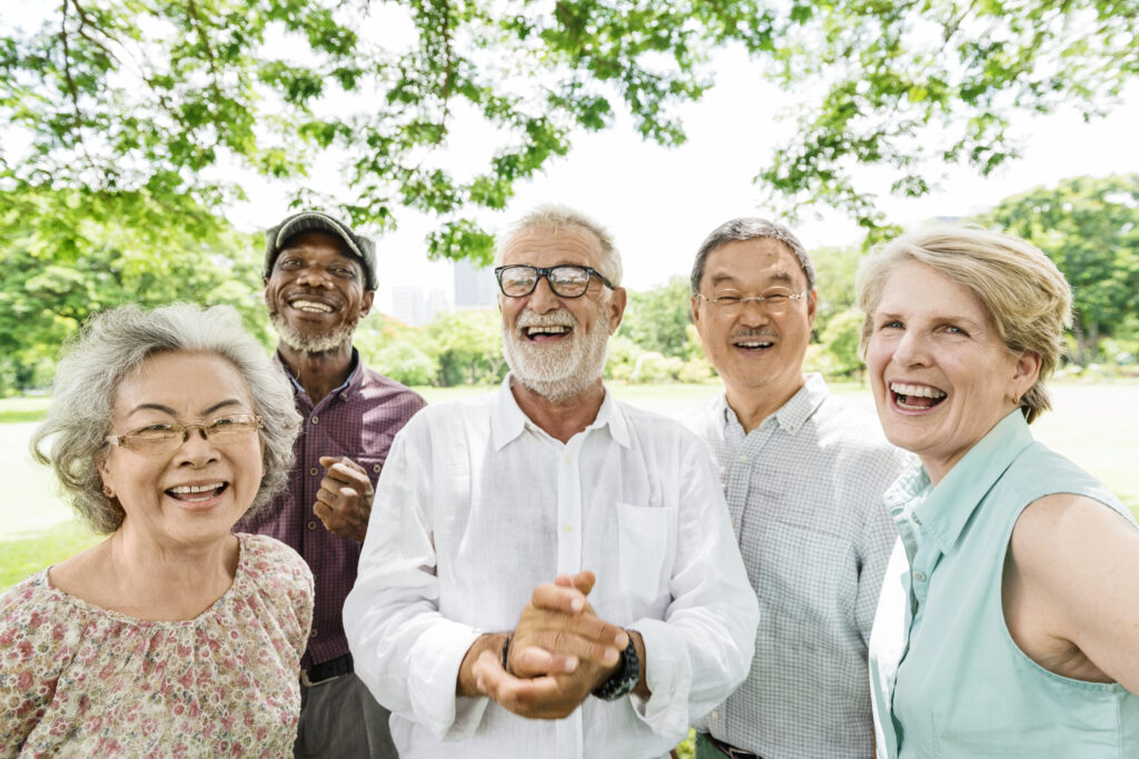 Residents laugh together under a tree in a park on a sunny day