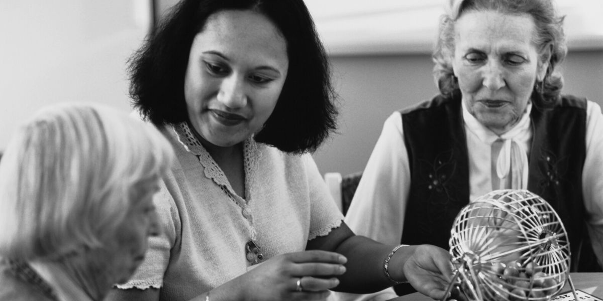 Caregiver-BINGO Black and white photo of a caregiver with two senior women